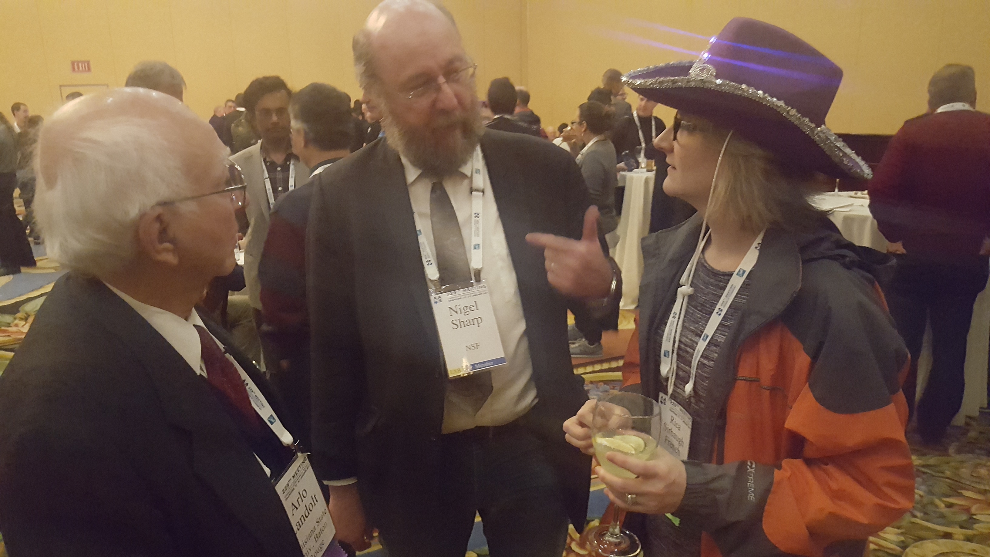 Arlo, Nigel Sharp, and me chatting at an AAS229 reception while I wear my hat.