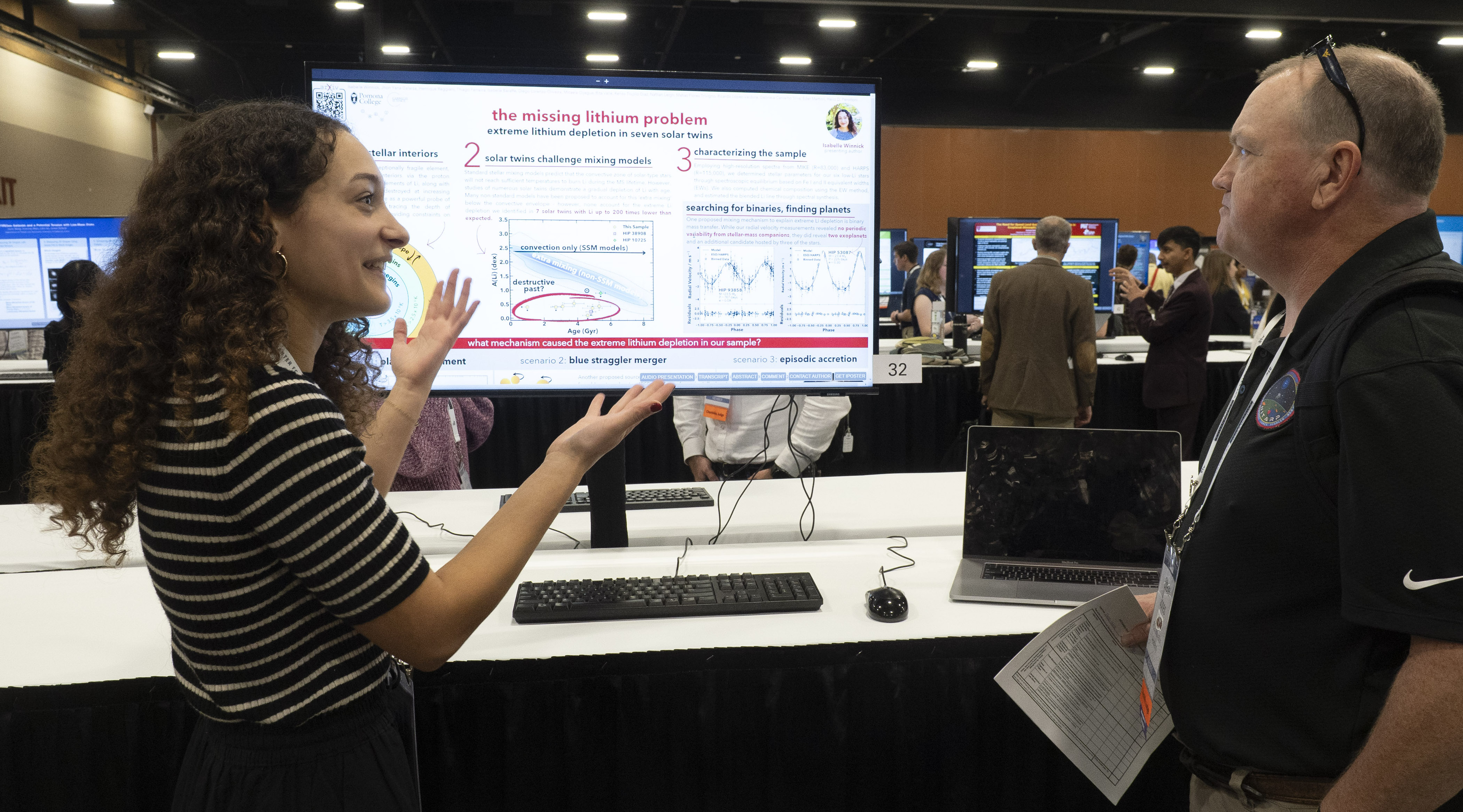 A student (left) presenting an iPoster (center) to a judge (right)